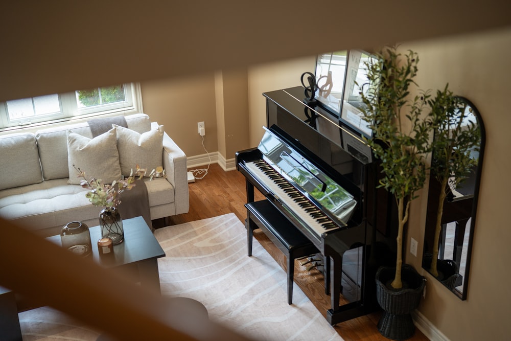 Piano droit noir adossé au mur d’un salon, à côté d’un canapé